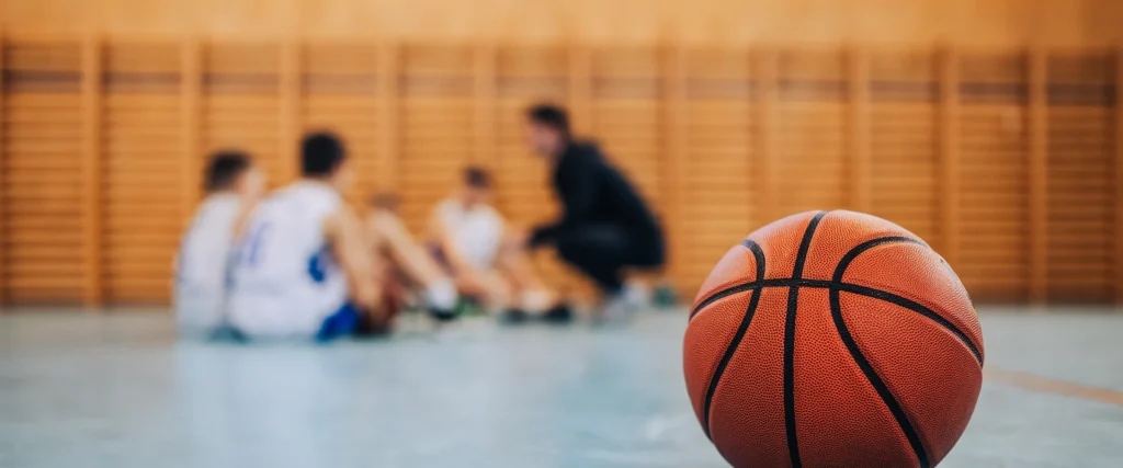 coach with team, basketball in foreground